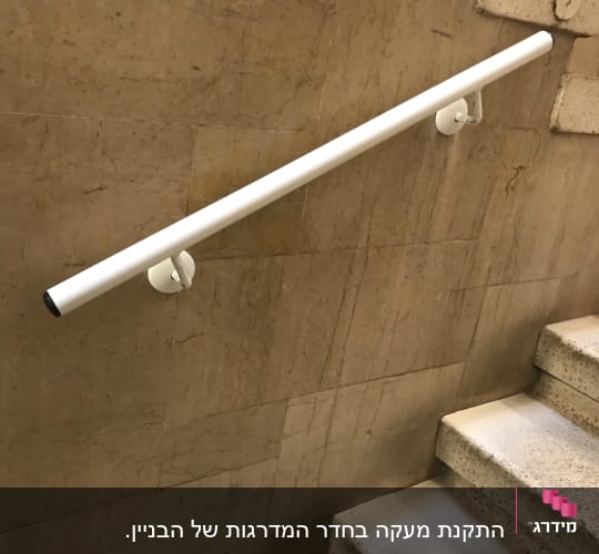 מעקה לבן מותקן על קיר מדרגות פנימי